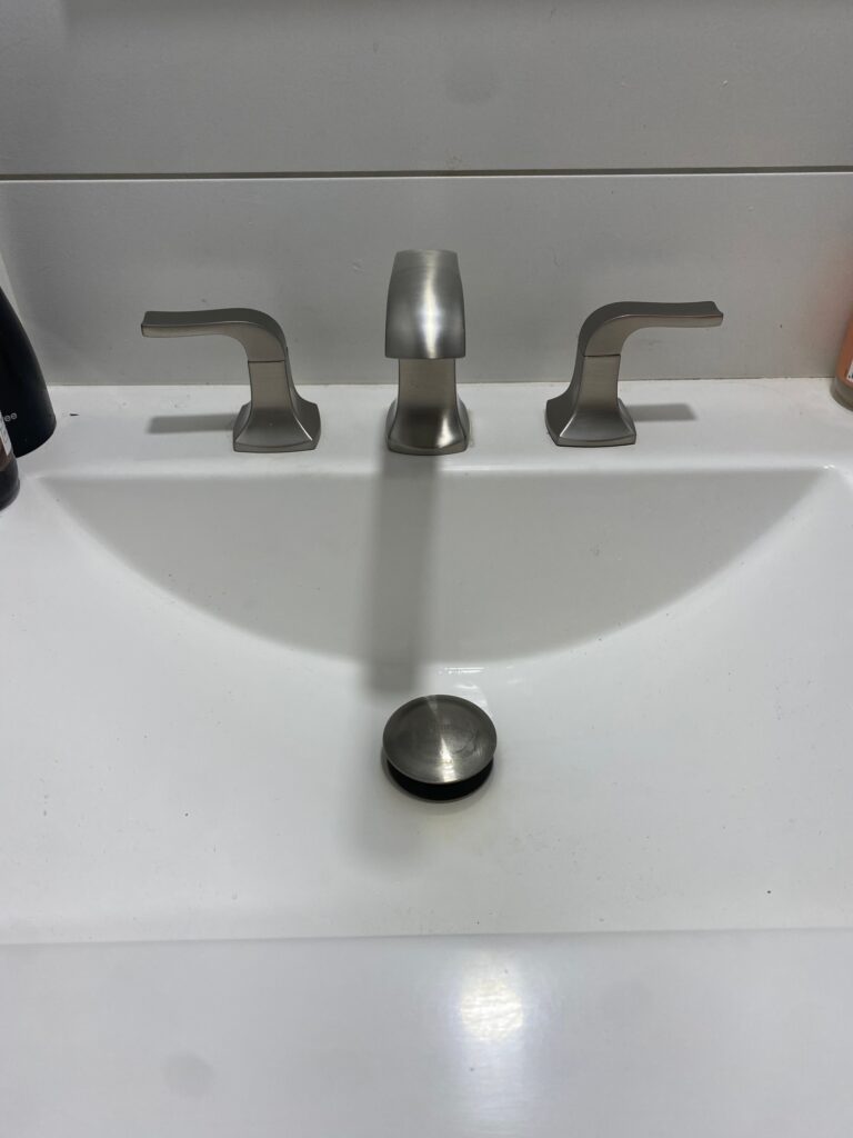 Modern bathroom sink faucet with dual handles and a pop-up drain stopper, showcasing plumbing fixtures suitable for water services in Orange County.