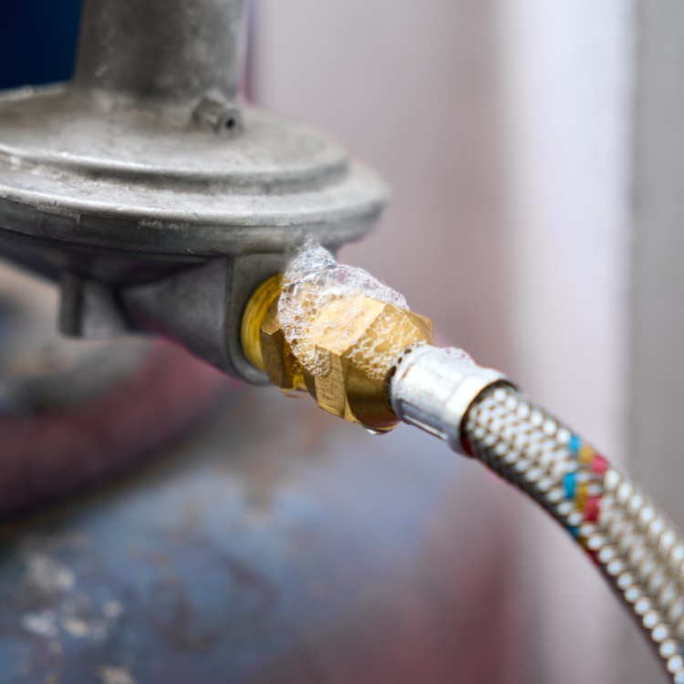 Close-up of a plumbing connection with a brass fitting and water bubbles, illustrating potential leak repair services by Plumbing By Tony.