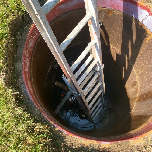 Ladder positioned inside a sewer line access point, showcasing trenchless repair methods and plumbing infrastructure relevant to sewer line services in Huntington Beach, CA.
