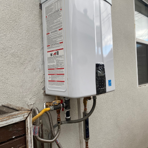 Tankless water heater installation on exterior wall, featuring connections for gas and water supply, with safety and operation instructions visible.