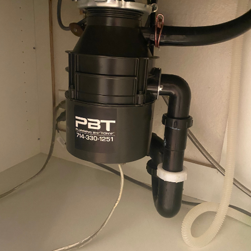Garbage disposal unit labeled "PBT Plumbing By Tony" with contact number 714-330-1251, installed under a kitchen sink, showcasing plumbing infrastructure relevant to drain cleaning services in Huntington Beach, CA.