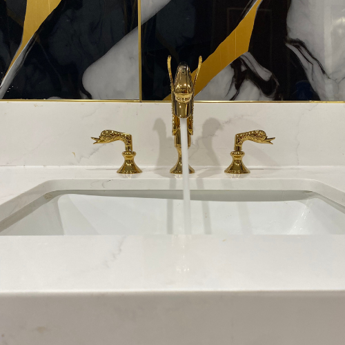 Elegant bathroom sink with gold faucets and flowing water, showcasing modern plumbing design and craftsmanship.