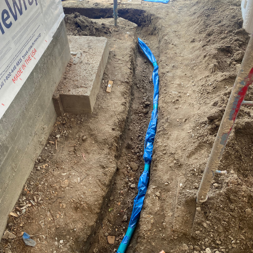 Plumbing By Tony Trench with blue plumbing pipe installation in a construction site, highlighting emergency plumbing work and compliance with safety standards.